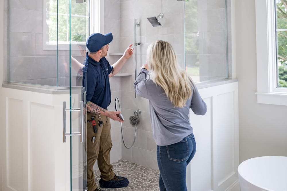 Plumber showing client shower head during a plumbing installation appointment.