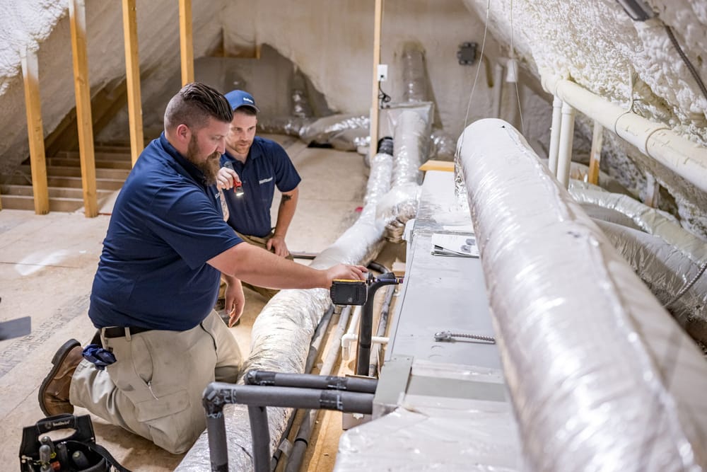 Notturno team members standing in front of duct work, completing a new home inspection.