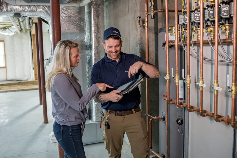Plumber showing client an Ipad during a seasonal plumbing service.