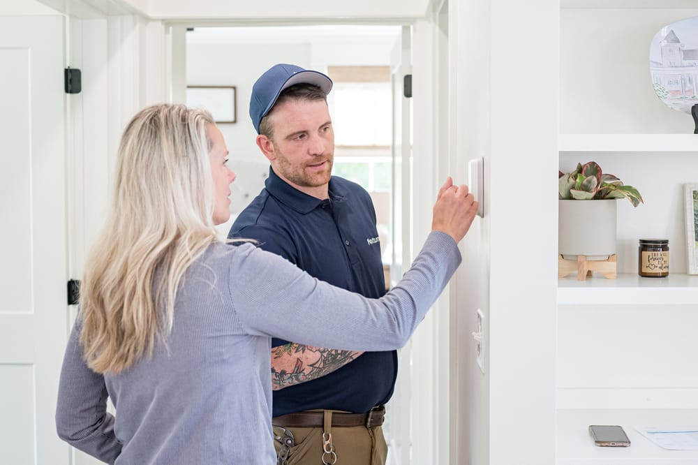 Technician showing client how to work a newly installed thermostat.