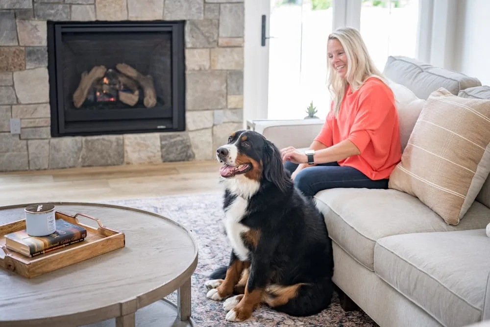 Woman and dog sitting on couch.
