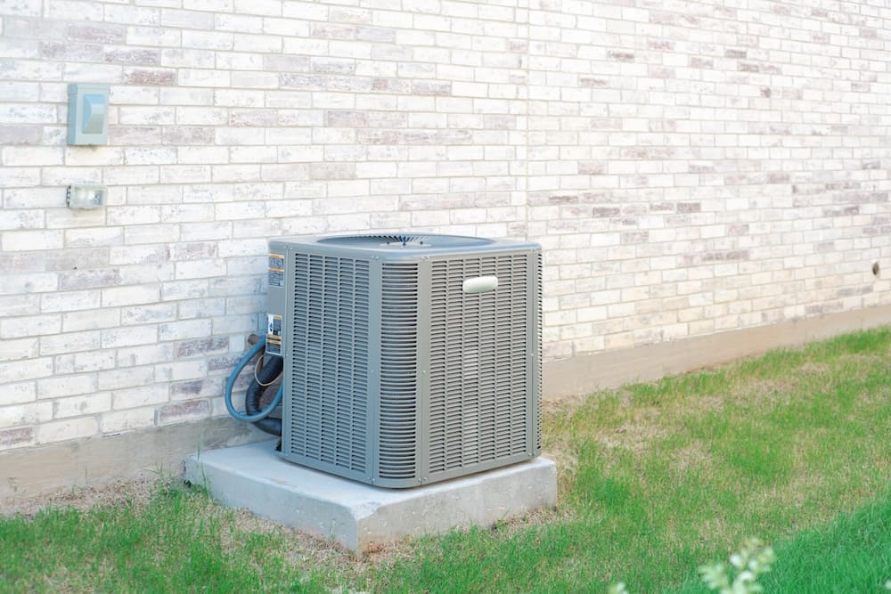 Outdoor air conditioning on a concrete slab next to a residential home
