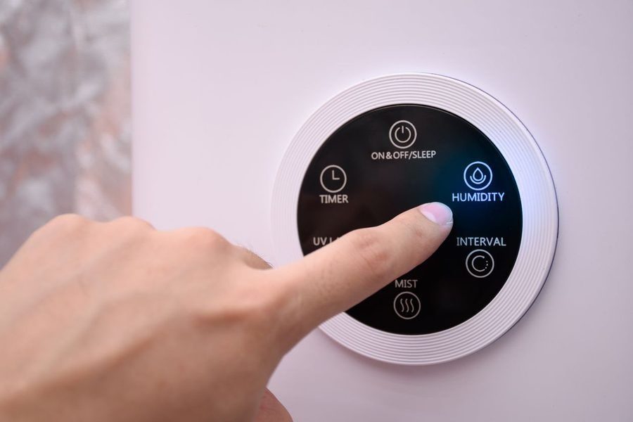 Close up man hand pressing the digital humidifier button on a smart humidifier in a smart home