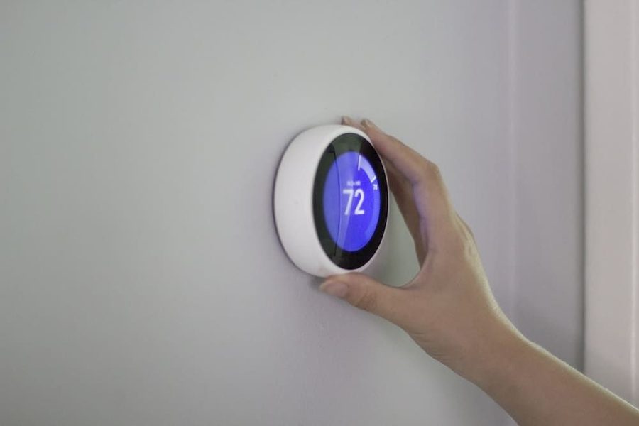 Homeowner adjusting the temperature on their smart thermostat that displays 72 degrees.