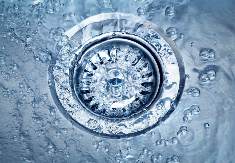 Cleared drain with water flowing down it. There is a drain stopper to catch any food or debris to prevent clogs.