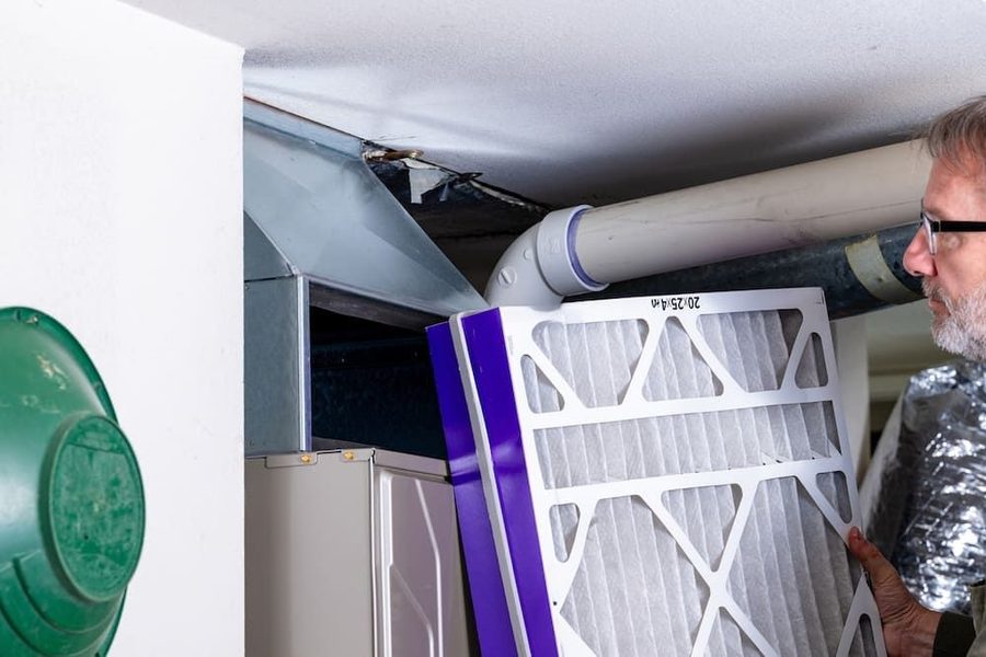 HVAC technician replacing a furnace filter as part of its seasonal maintenance